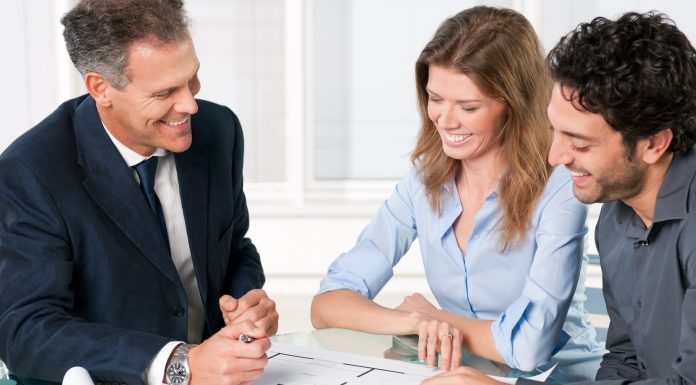Happy young couple discussing with an estate agent about their new house plans